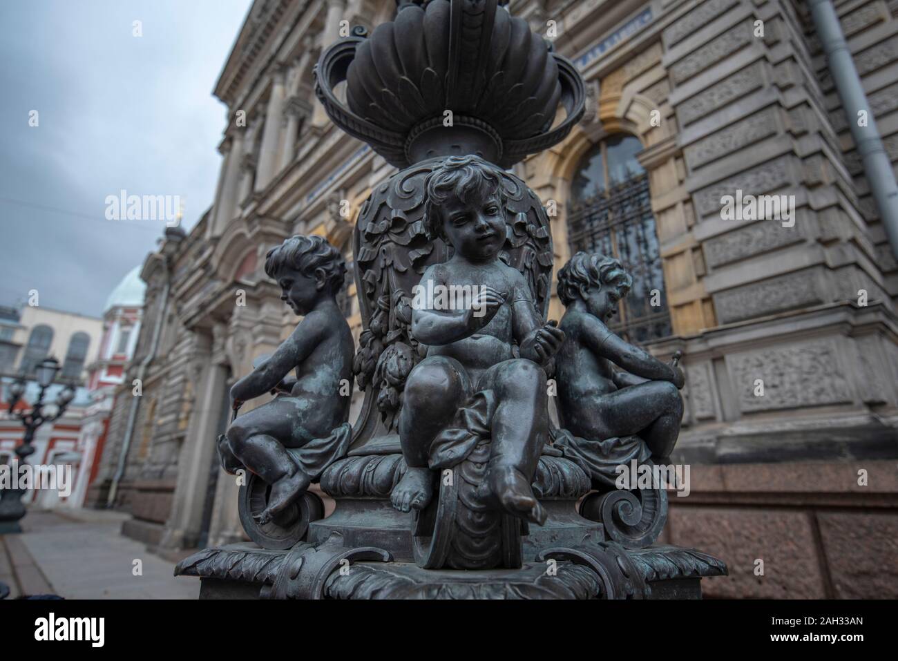Bronze angel boy statue with a human figure in hands. Part of street lantern composition in front of Stieglitz Art Academy in SAINT PETERSBURG, RUSSIA Stock Photo