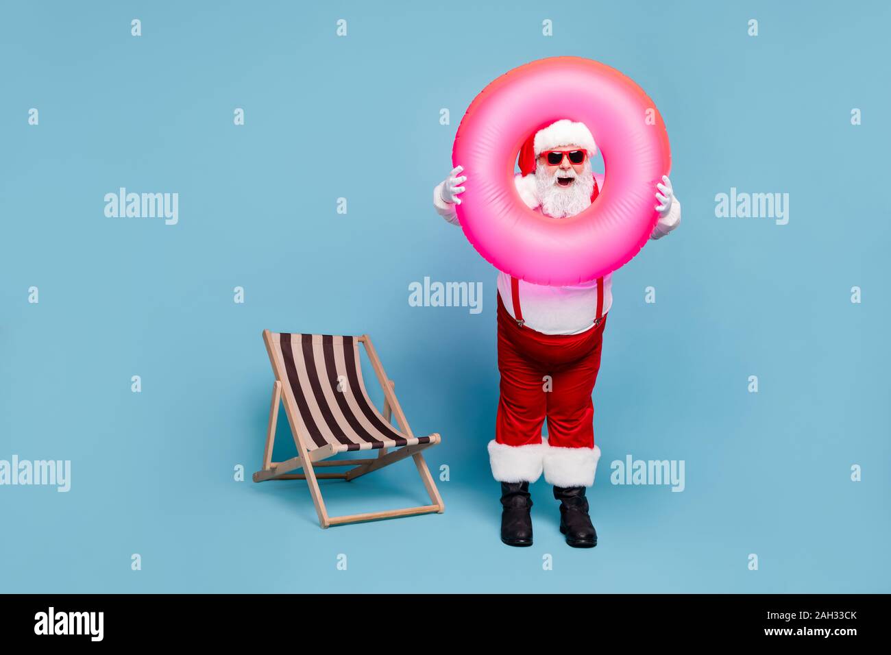 Full length body size view of his he nice cool comic glad cheerful cheery fat Santa carrying pink swimming circle having fun resort isolated over blue Stock Photo