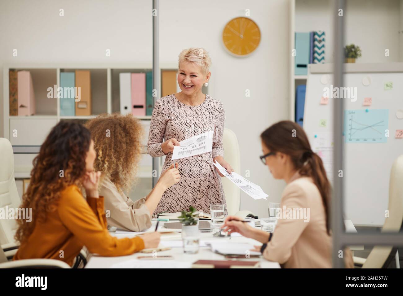 Mature female boss having active discussion with her emplyees at business meeting, horizontal eye level shot Stock Photo