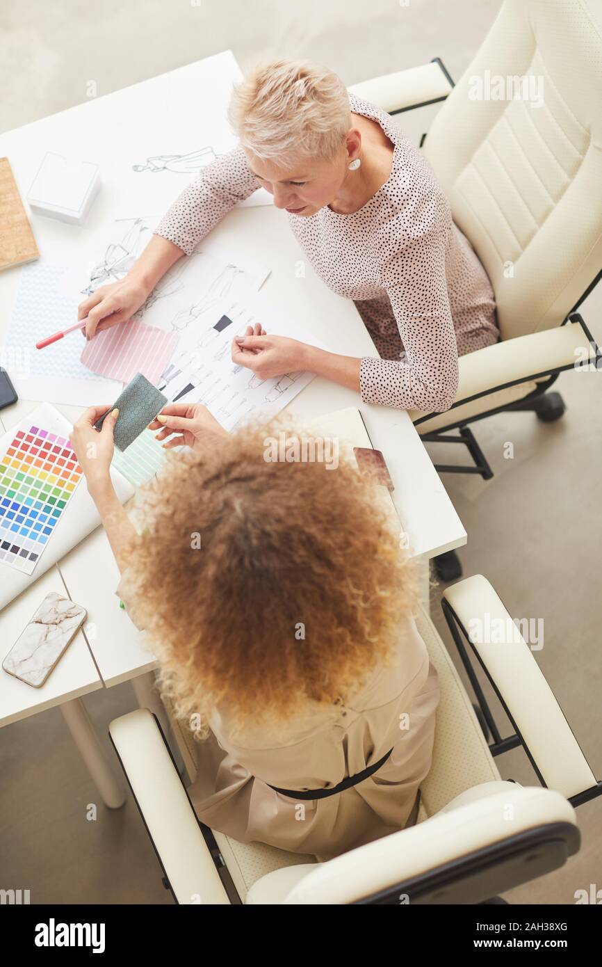 Two stylish women working together choosing best clothes design vertical high angle shot Stock Photo
