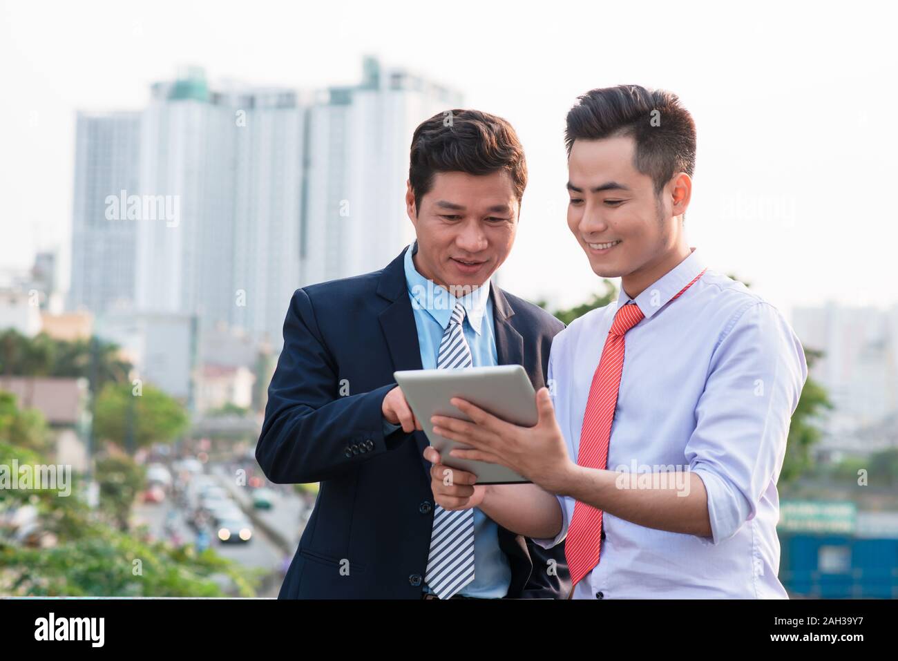 Young handsome businessmen discussing project on digital tablet computer outdoors Stock Photo
