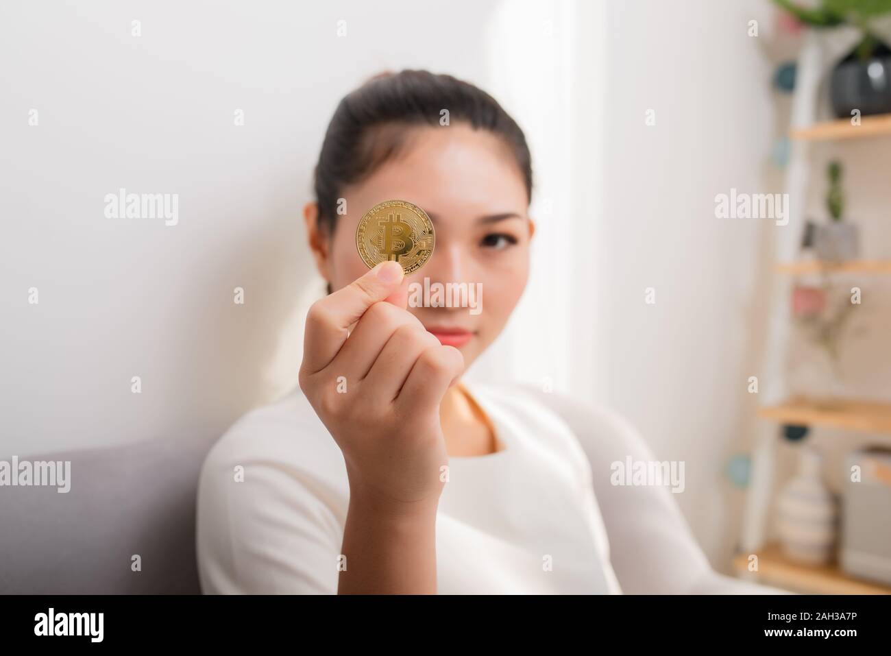 Asian woman gets big money! Attractive woman with holds bitcoin in hands and looks into the camera. Stock Photo