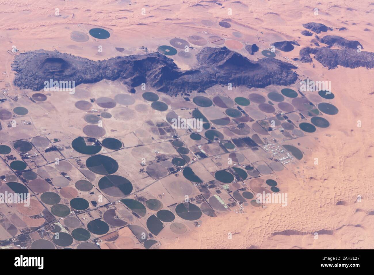 View from the air of round irrigation fields and farms surrounded by sand dunes in the desert in Saudi Arabia Stock Photo