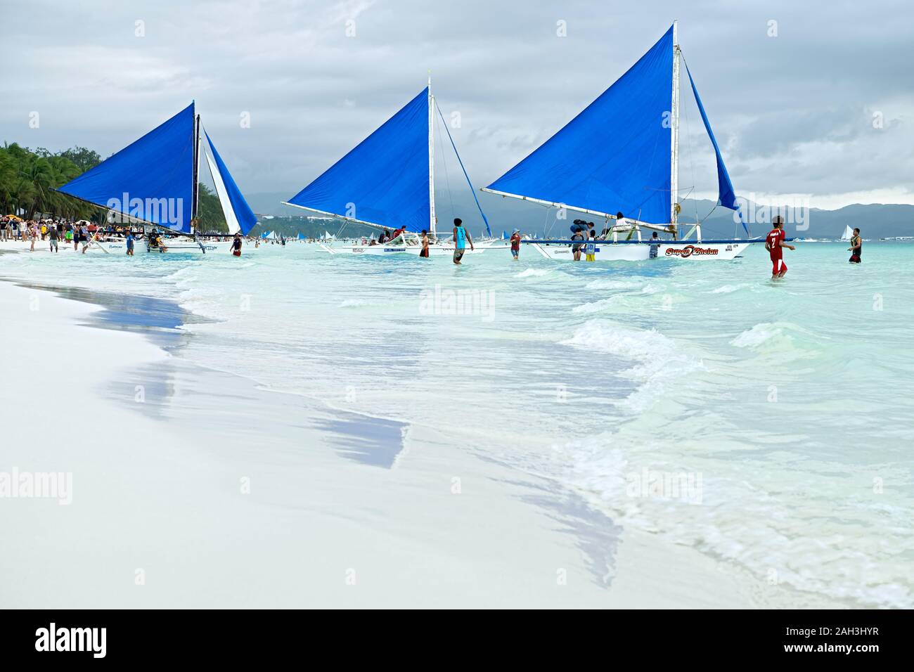 Boracay, Aklan Province, Philippines - January 6 2018: Three blue colored sailboats waiting along the clean White Beach for tourists Stock Photo