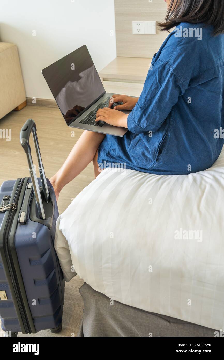 Woman using laptop putting on thigh while sitting on bed Stock Photo