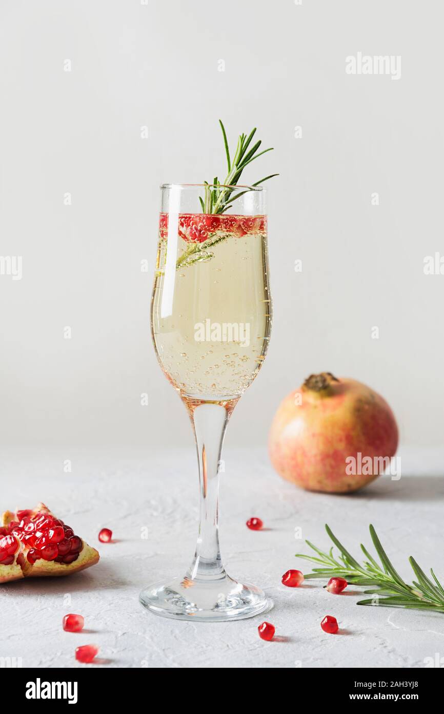 Pomegranate Christmas holiday cocktail with rosemary sprig, sparkling wine, club  soda on white table. Xmas drink. Close up Stock Photo - Alamy