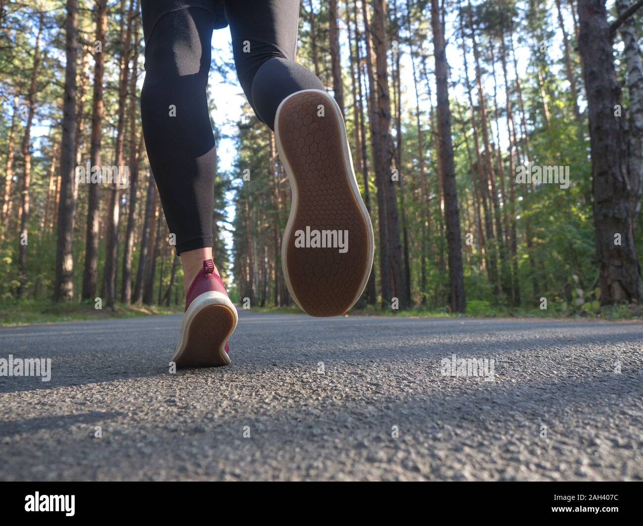 Feet of a runner. Young girl runs in the forest. Close-up of sneakers. Helathy lifestyle. Stock Photo