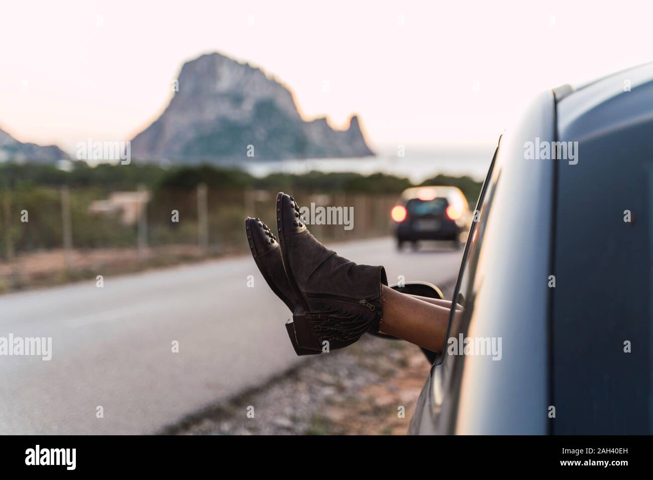 Young woman during road trip, leaning feet out of window Stock Photo
