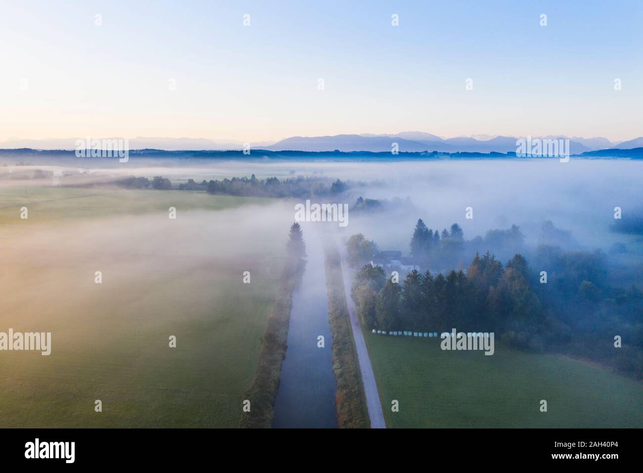 Germany, Bavaria, Geretsried, Aerial view of Loisach river canal at foggy dawn Stock Photo