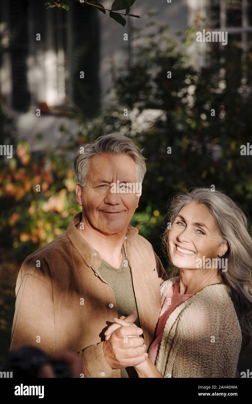 Portrait of happy senior couple in garden of their home in autumn Stock Photo