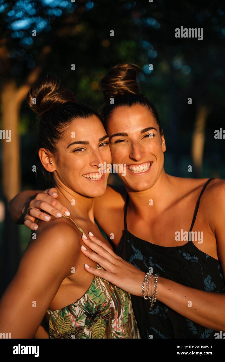 Portrait of two happy twin sisters embracing outdoors at sunset Stock ...