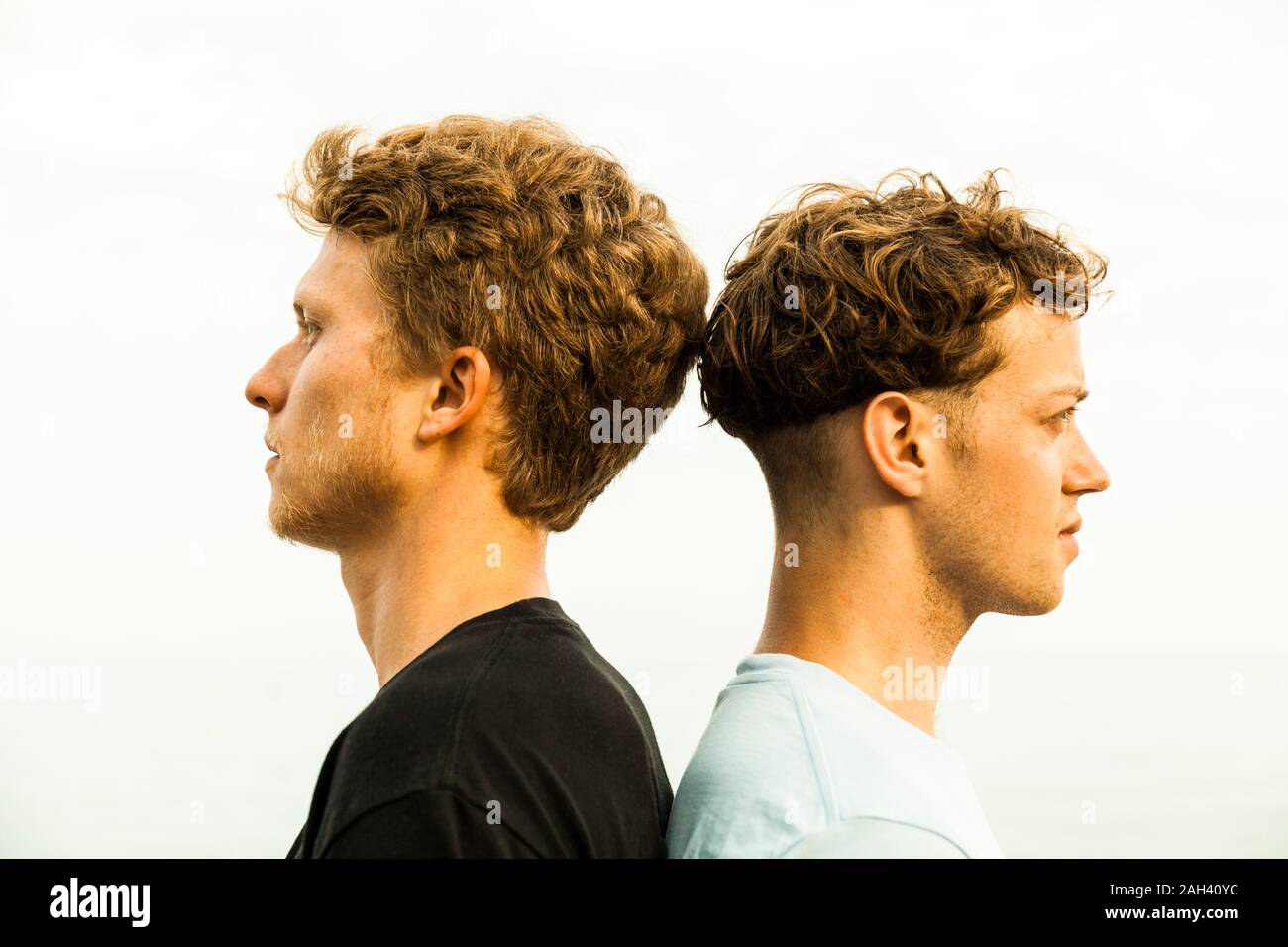 Portrait of strawberry blonde young men, back to back Stock Photo