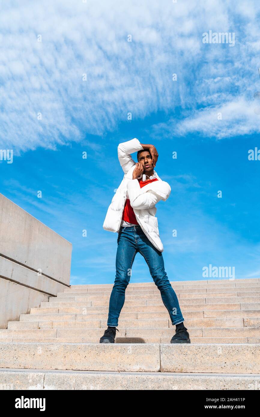 Young man standing on stairs outdoors with hands on face Stock Photo