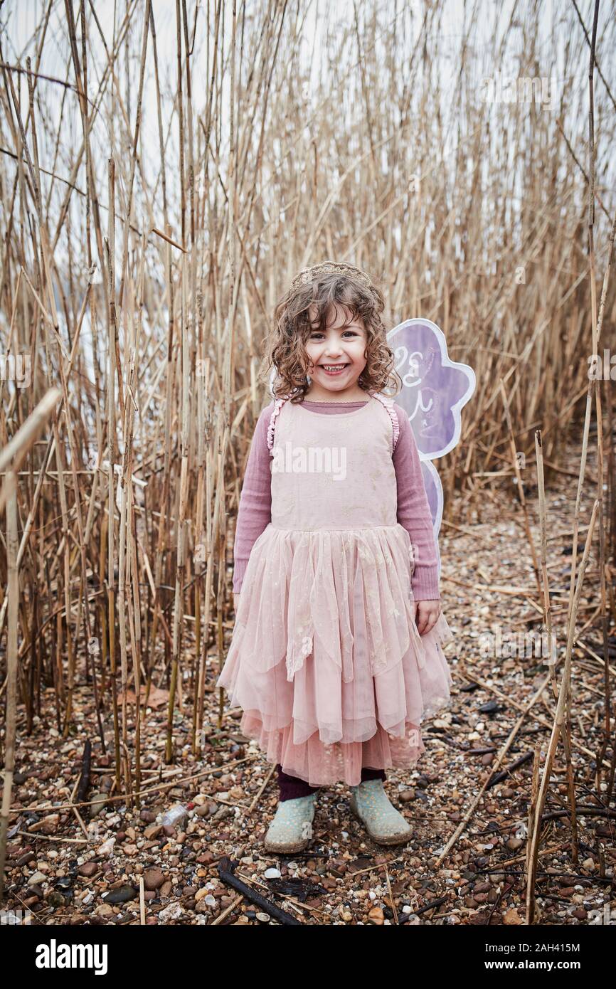 Portrait of happy little girl in nature dressed up as a butterfly Stock Photo