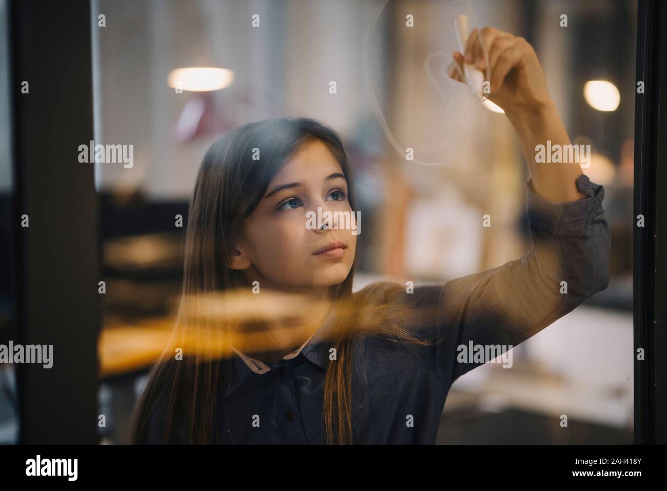 Girl drawing on glass pane in office Stock Photo