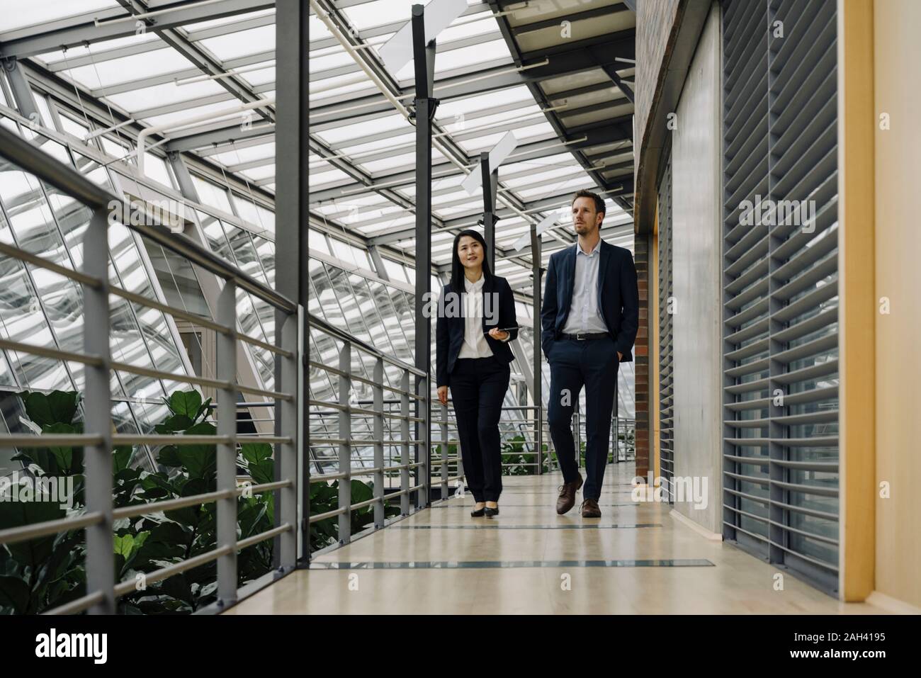 Businessman and businesswoman walking in modern office building Stock Photo