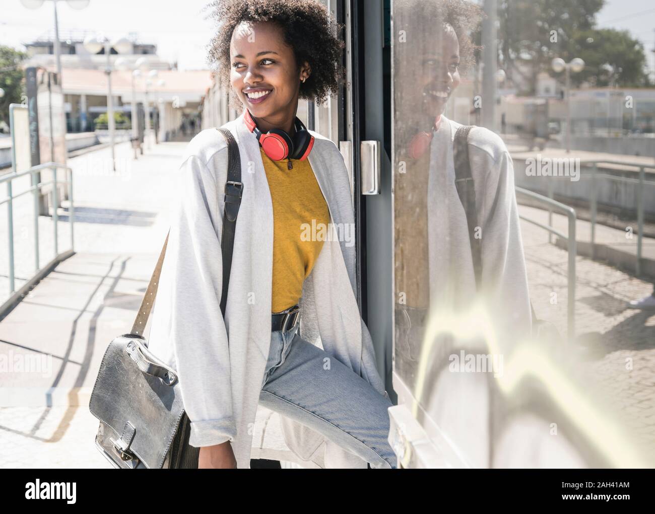 Smiling young woman entering a train Stock Photo