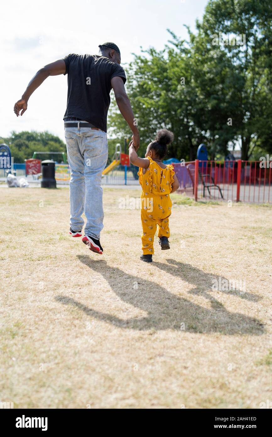 Rear view of father and daughter walking hand in hand in a park Stock ...