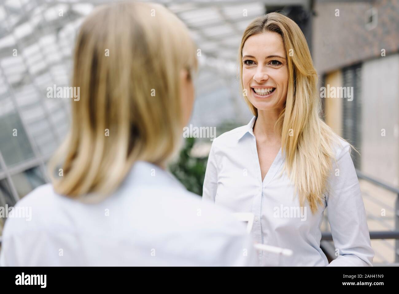 Portrait of young businesswoman smiling at colleague in office Stock Photo