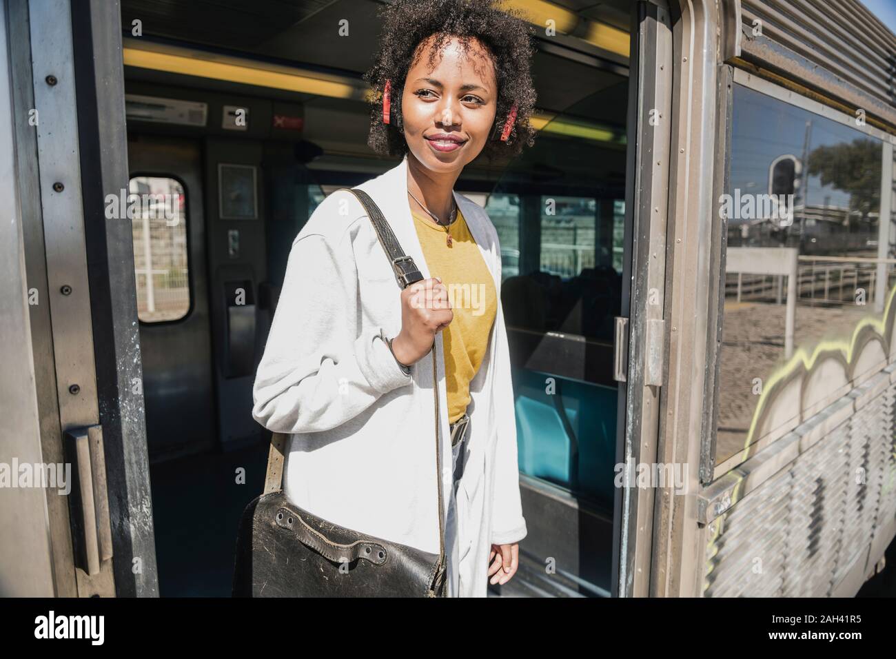 Smiling young woman standing in train door Stock Photo