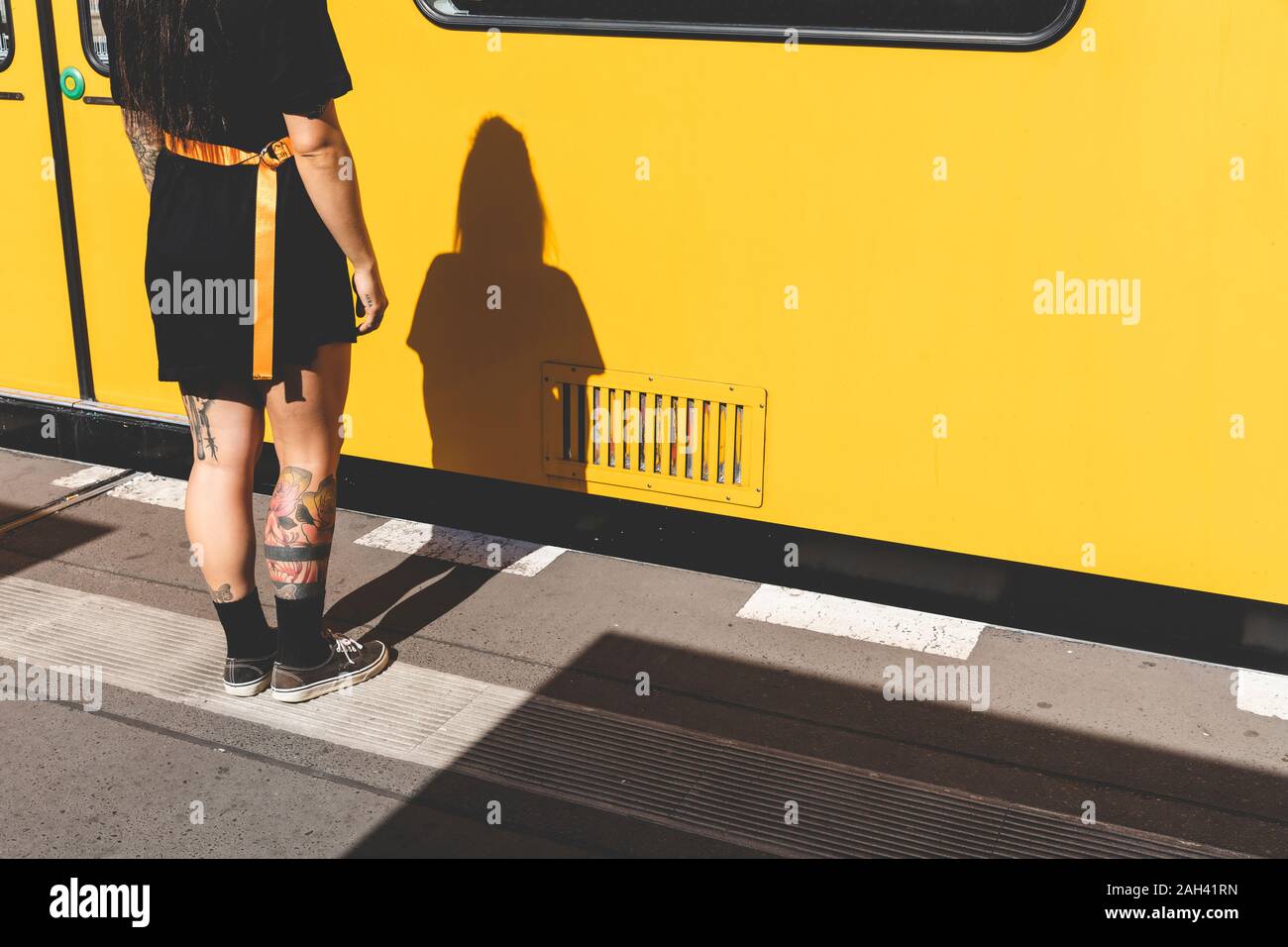 Back view and shadow of tattooed young woman standing at platform, Berlin, Germany Stock Photo