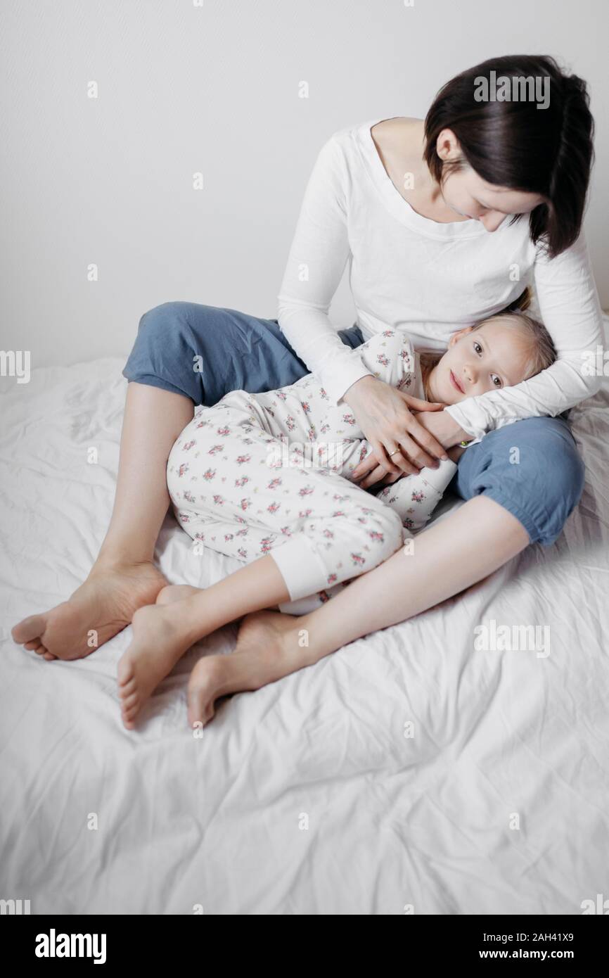 Mother hugging her daughter on bed Stock Photo