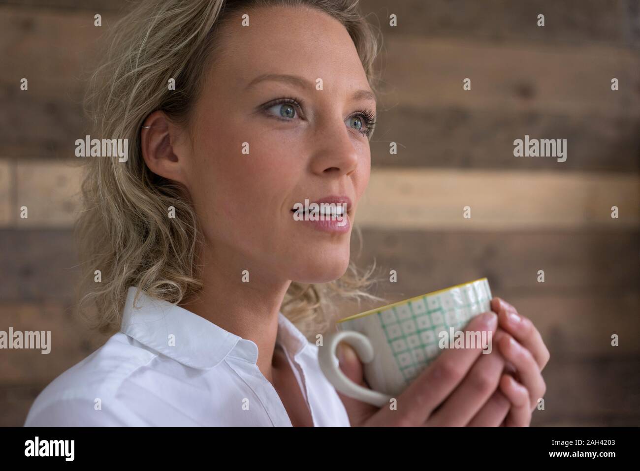 Young businesswoman holding cup of coffee looking sideways Stock Photo