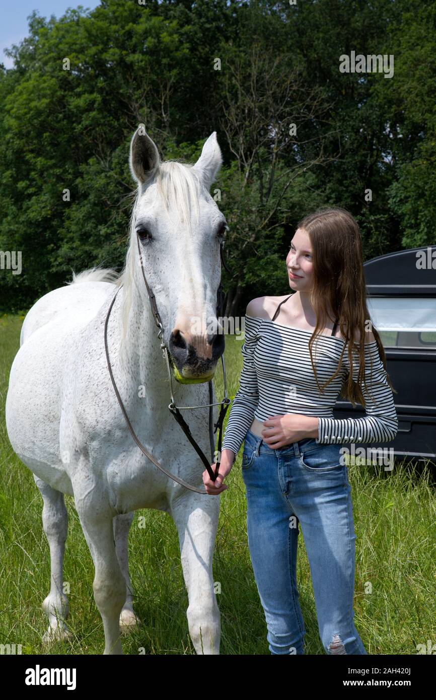 Happy teenage girl standing on a meadow with horse Stock Photo - Alamy