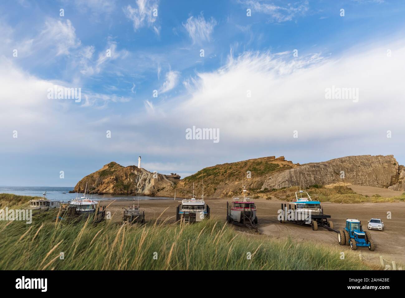 Ships at the beach with lighthouse in the back, Castlepoint, New Zwealand Stock Photo
