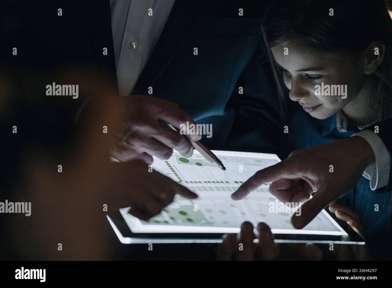 Business people and girl looking at shining construction plan on tablet in office Stock Photo