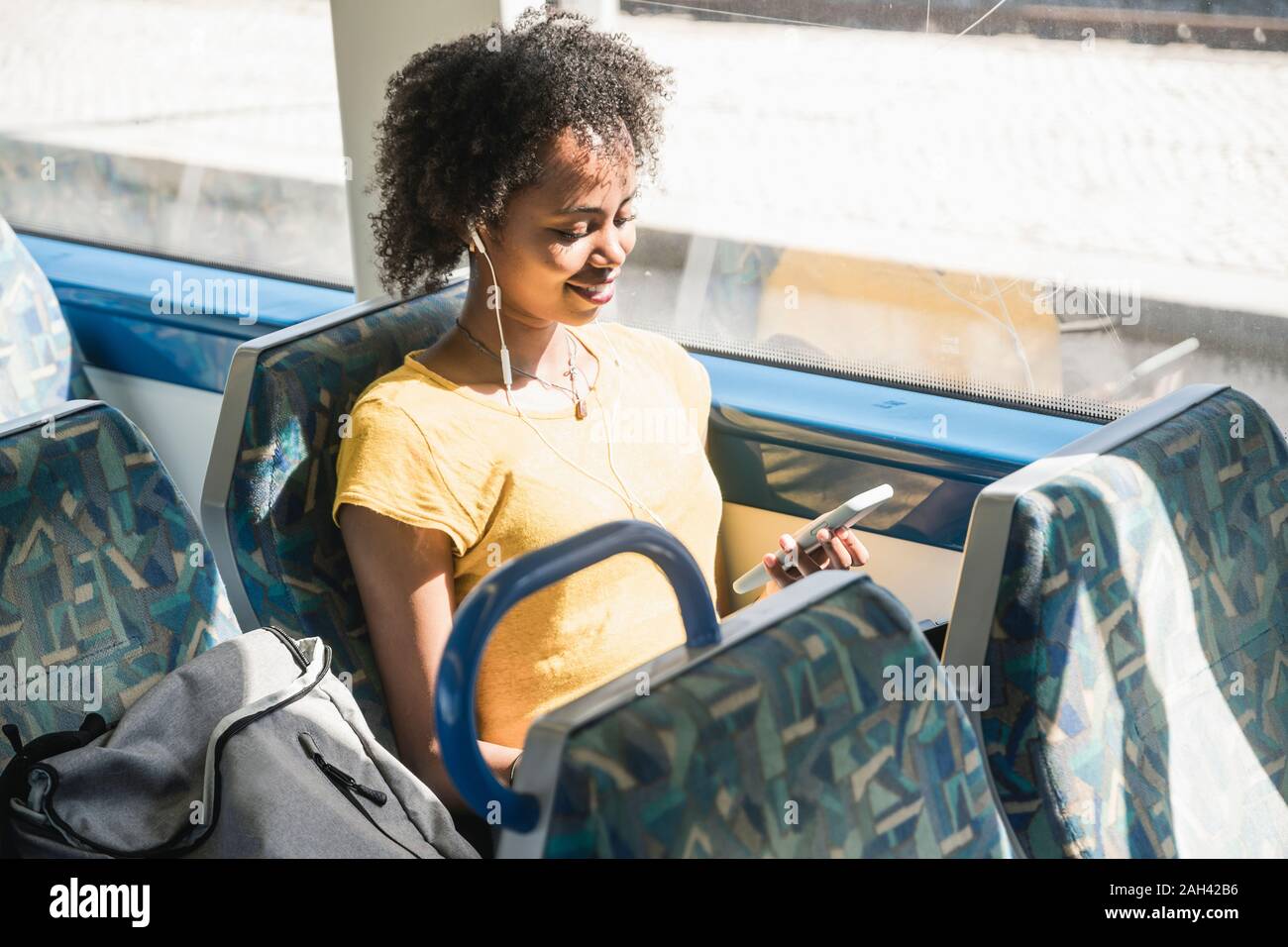 Young woman with earphones using smartphone on a train Stock Photo