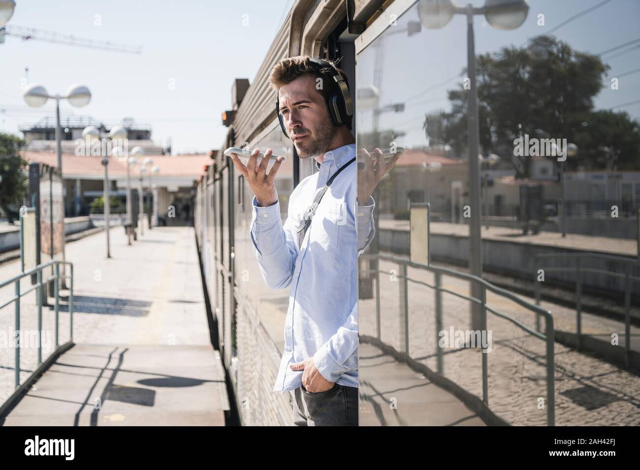 Young man with headphones using smartphone in train door Stock Photo