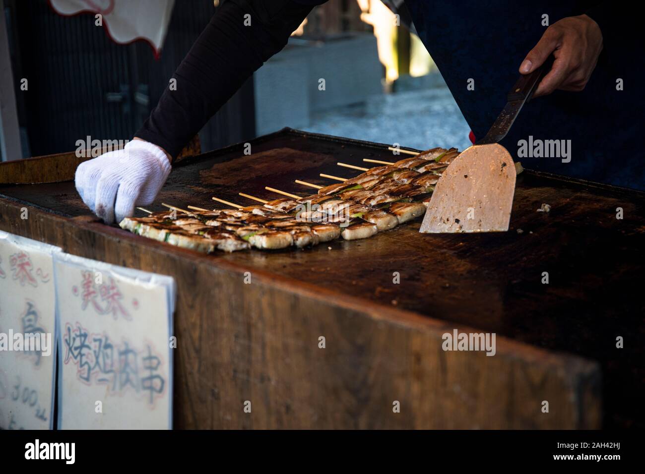 Japan, Kyoto Prefecture, Kyoto City, Hands of chef preparing yakitori at food stand Stock Photo