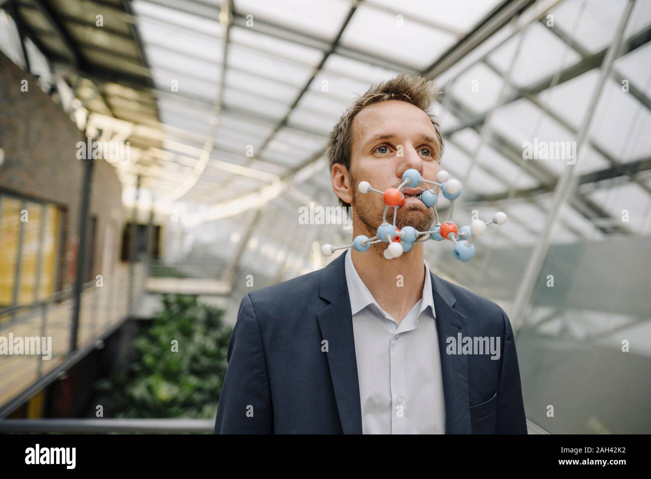 Portrait of businessman with atomic modelin his mouth Stock Photo
