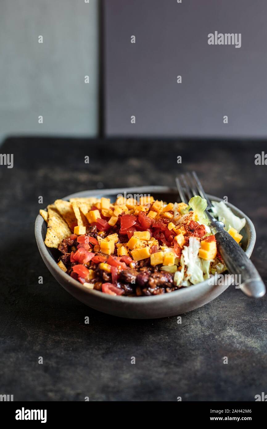 Bowl of nachos with, chili con carne, rice, lettuce, cheese and tomatoes Stock Photo