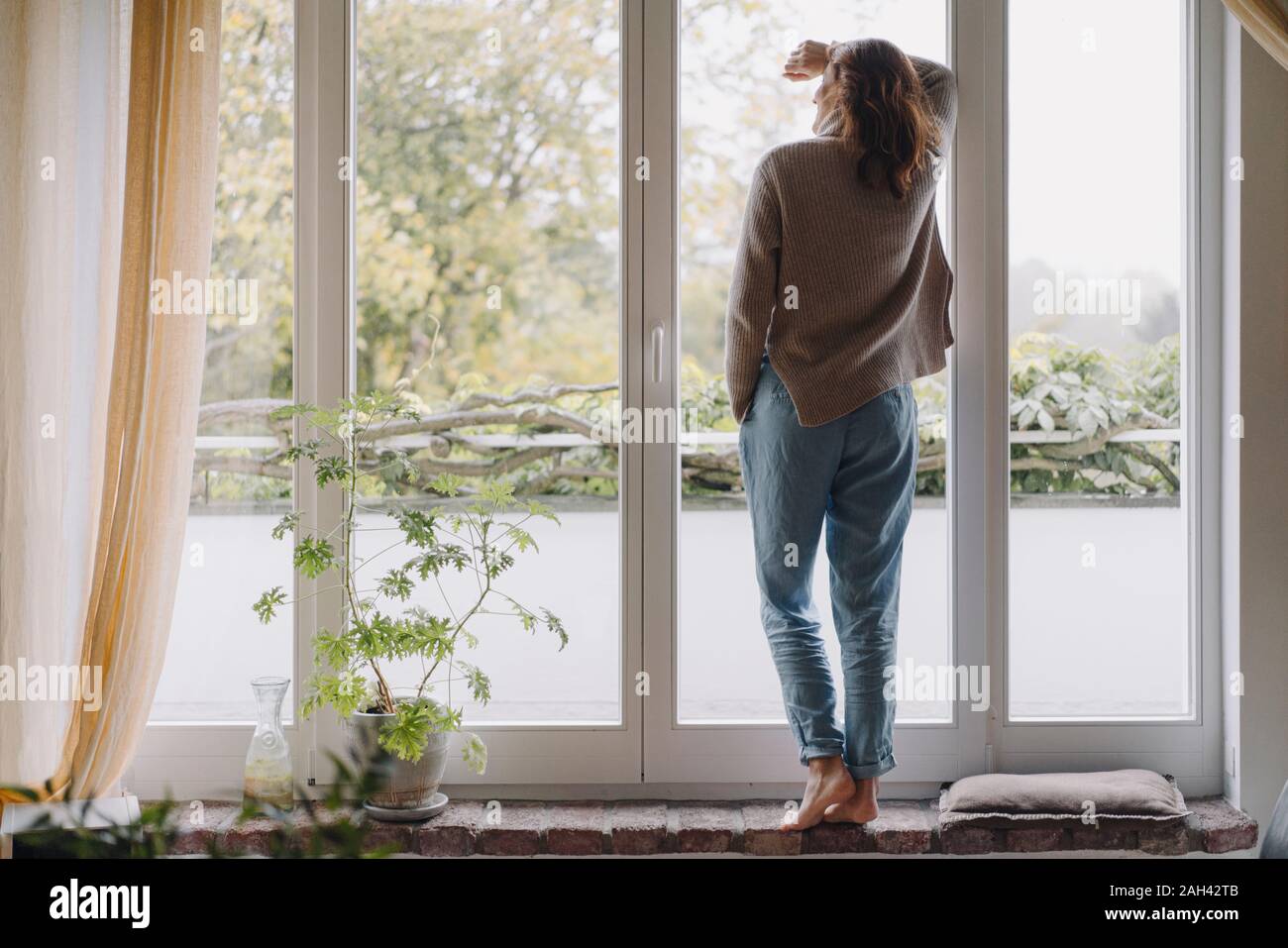 Woman looking out of window, rear view Stock Photo