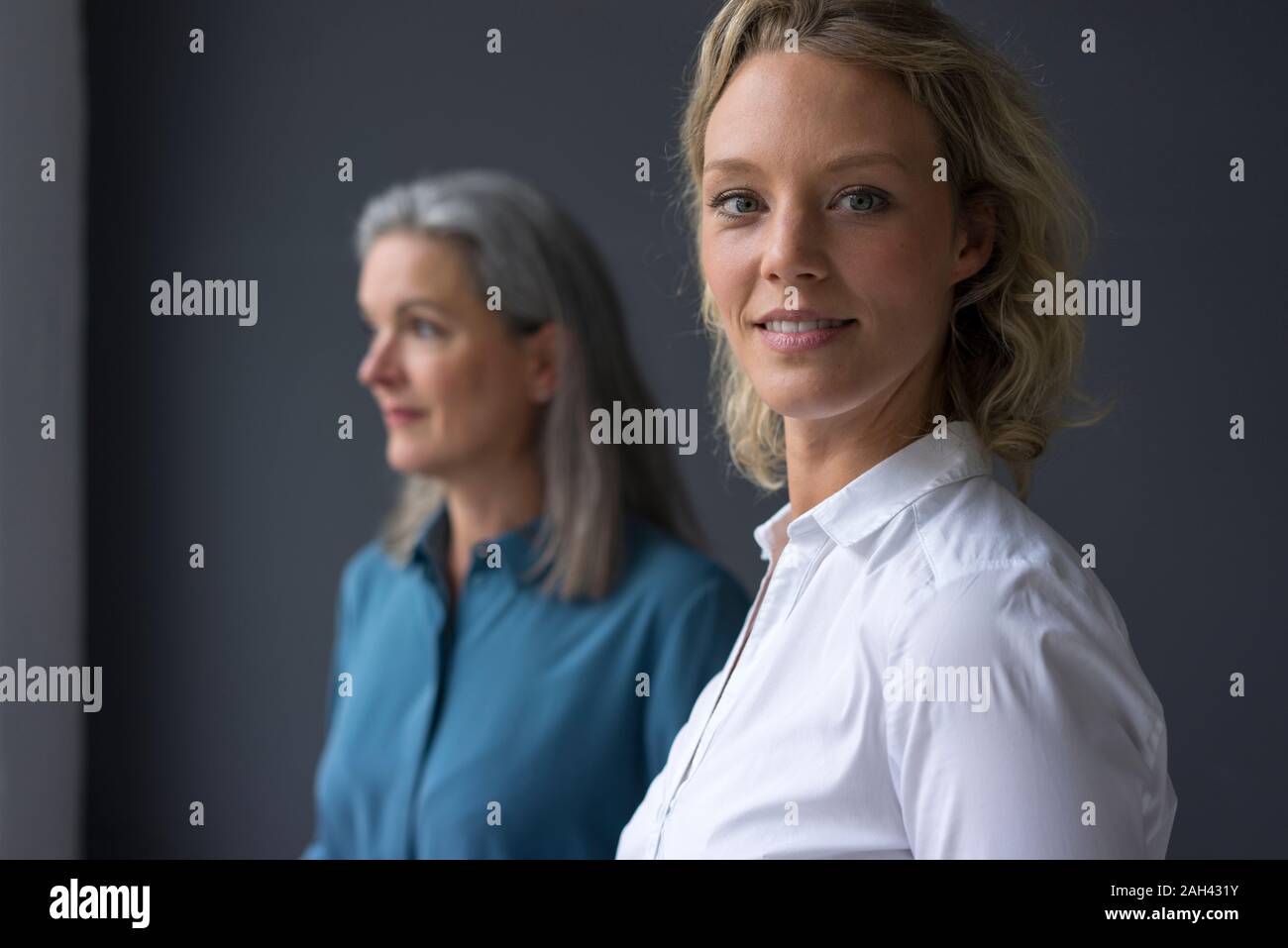 Portrait of smiling young businesswoman with mature businesswoman in background Stock Photo