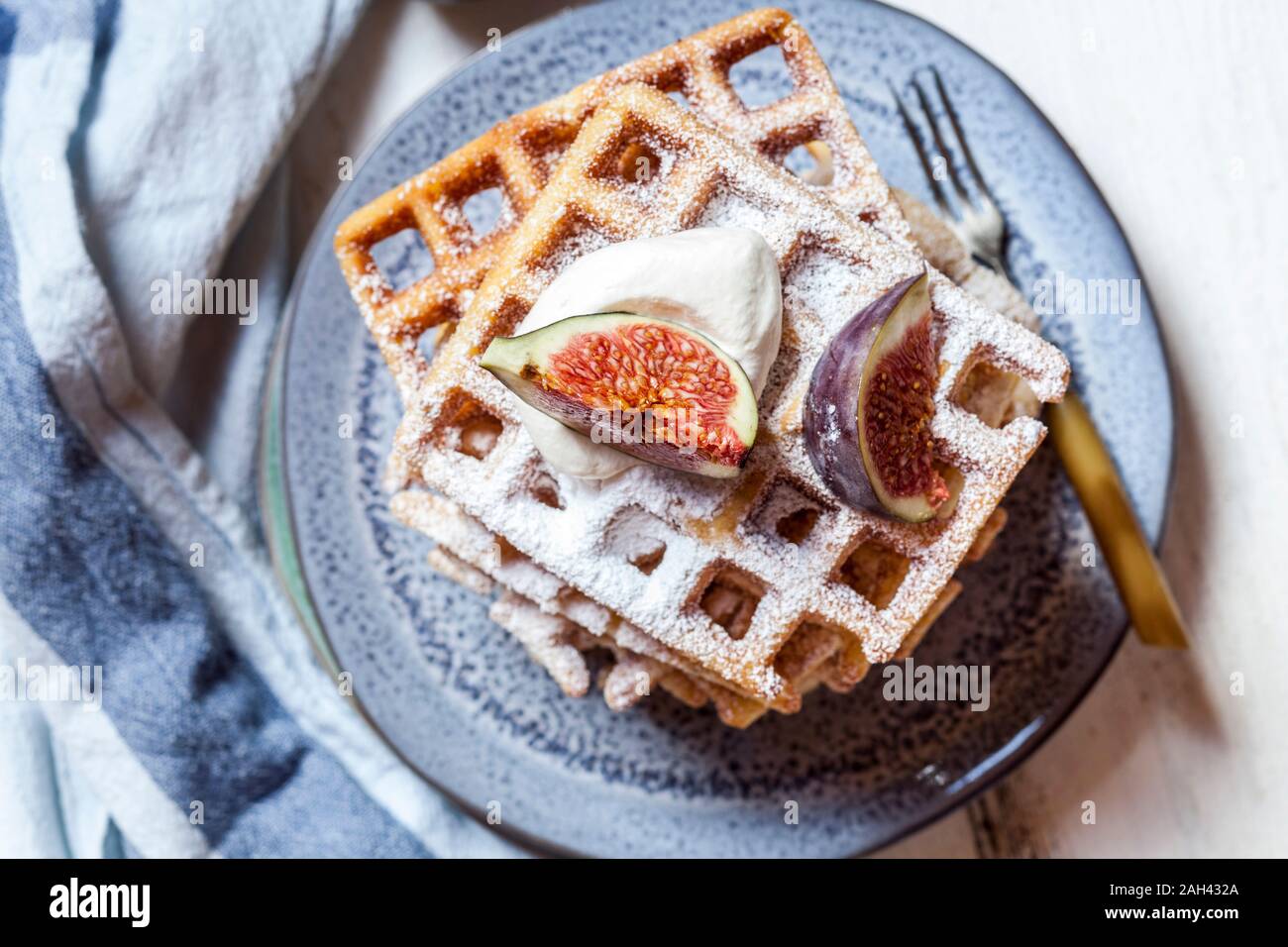 Plate of thick Belgian waffles with whipped cream, powdered sugar and figs Stock Photo