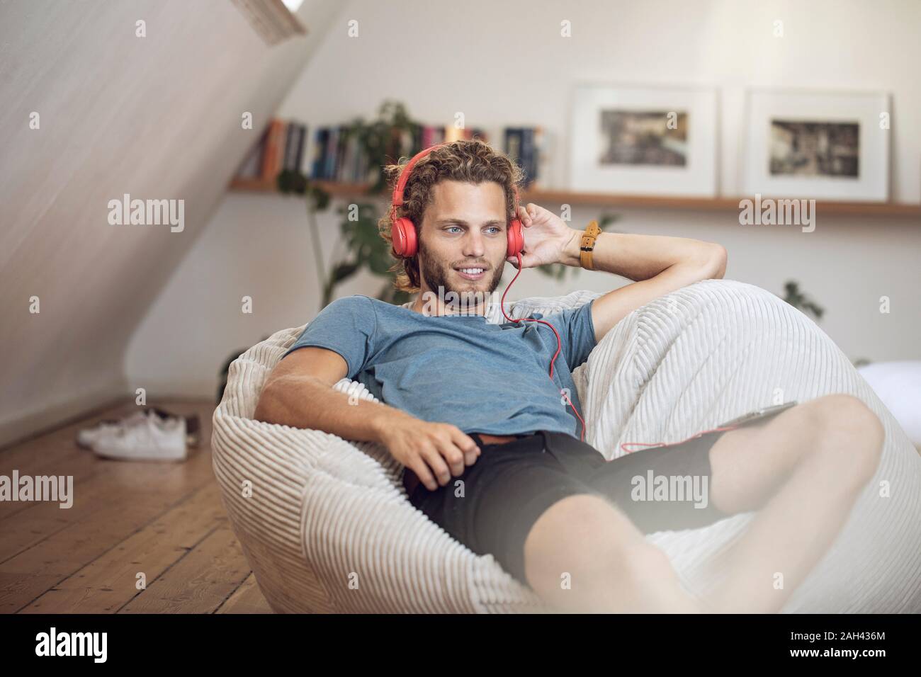 Young man relaxing in beanbag at home listening to music Stock Photo