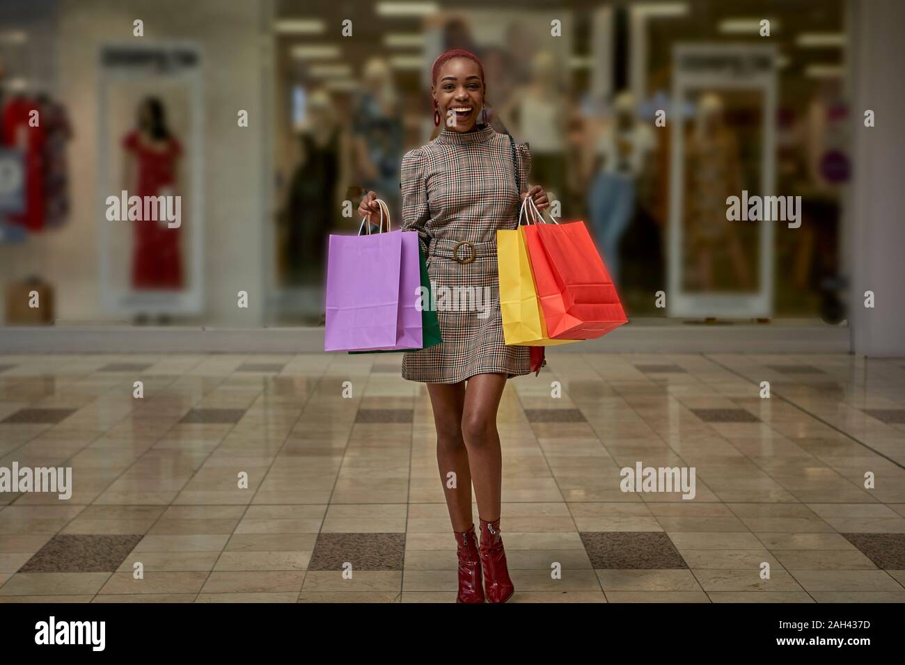 Happy young woman holding colorful shopping bags walking outside a shop Stock Photo