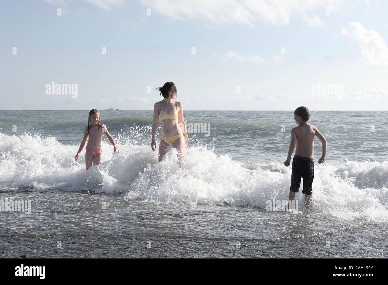 Happy mother with two kids having fun in the sea Stock Photo
