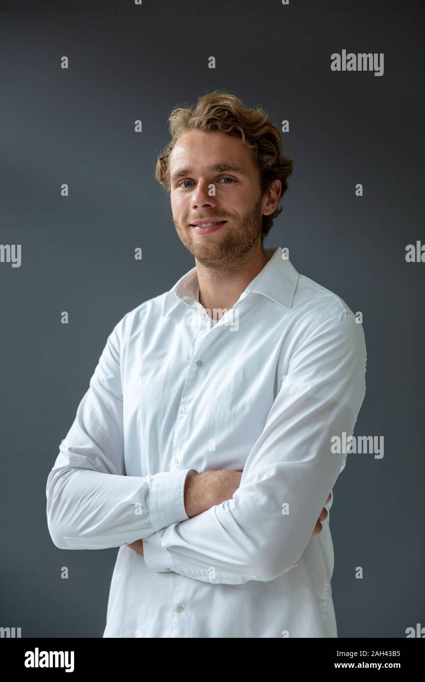 Portrait of young smiling businessman, wearing white shirt, looking at camera Stock Photo