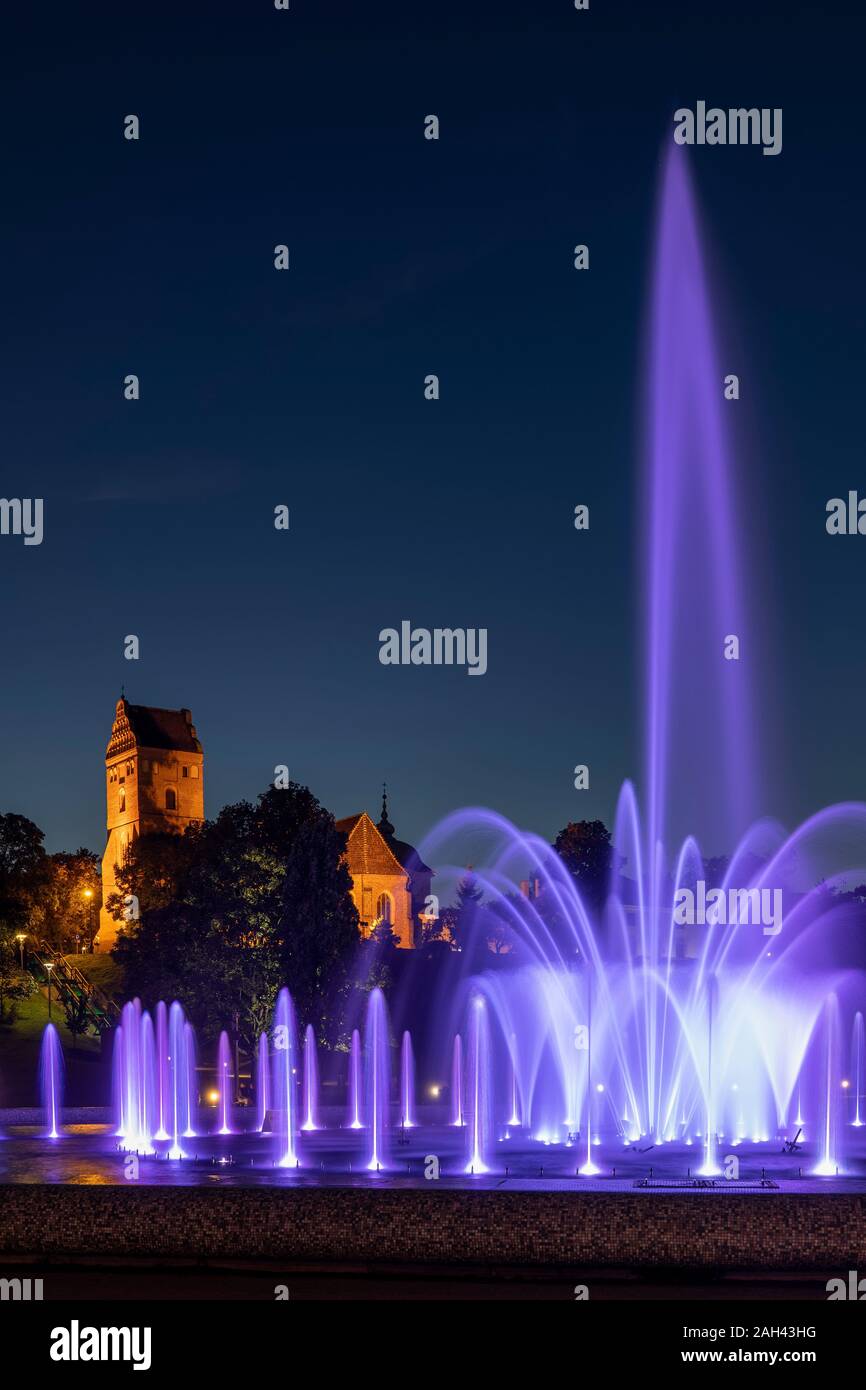 Poland, Masovian Voivodeship, Warsaw, Purple fountain in Multimedia Fountain Park at night with Saint Marys Church in background Stock Photo