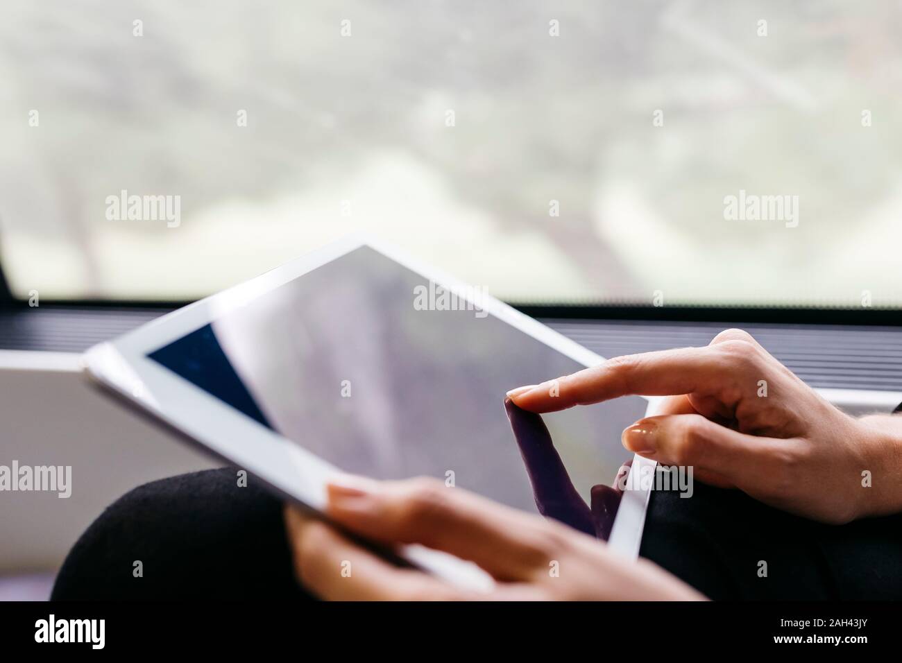 Woman's hand using a tablet while traveling by train Stock Photo