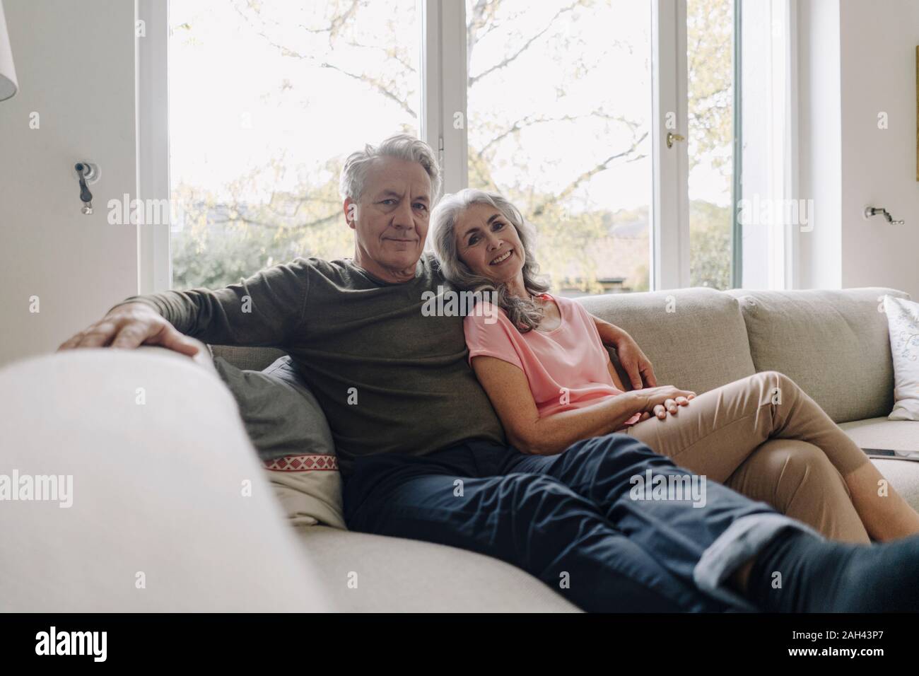 Portrait of senior couple relaxing on couch at home Stock Photo