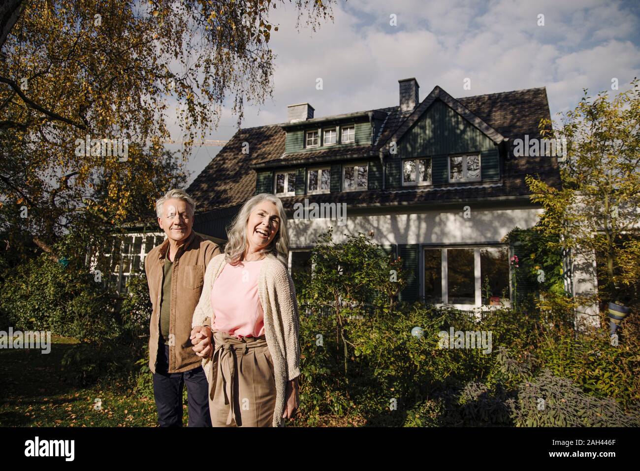 Happy senior couple in garden of their home in autumn Stock Photo