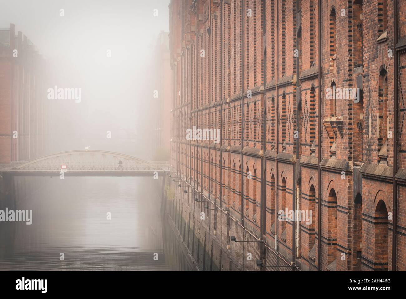 Germany, Hamburg, Speicherstadt, Building and footbridge over canal in fog Stock Photo