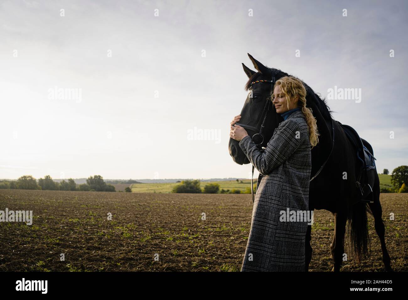 Affectionate young woman with horse on a field in the countryside Stock Photo