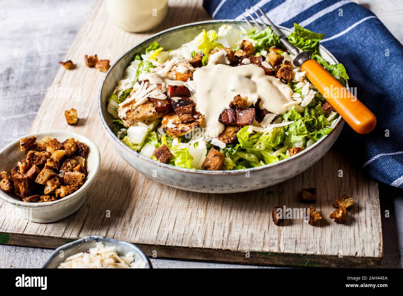 Bowl of Caesar salad with romaine lettuce, Parmesan cheese, bacon, chicken breast and croutons Stock Photo