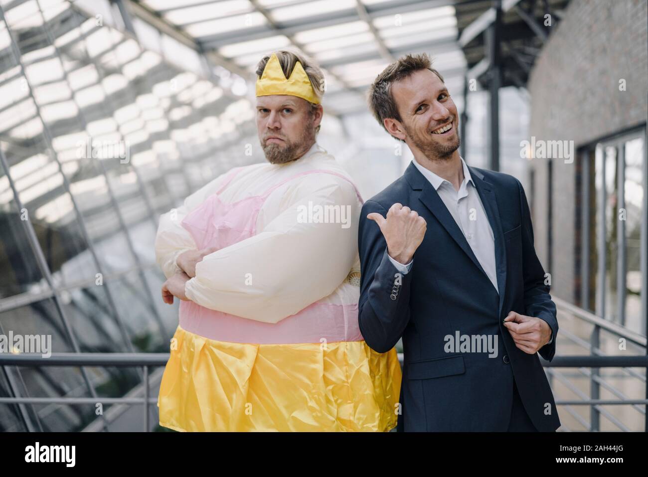 Laughing businessman pointing at man dressed up as a ballerina in office Stock Photo